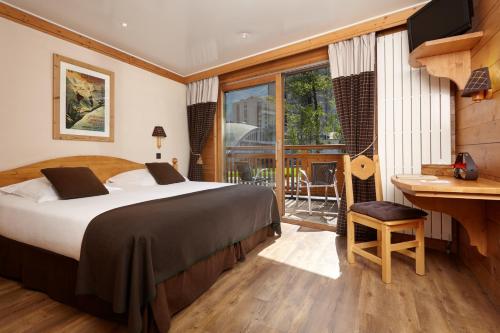 夏蒙尼-勃朗峰Hôtel de L'Arve by HappyCulture的一间卧室配有一张床、一张书桌和一个窗户。