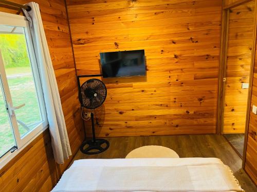 TeavaroBungalow TEIPO的一间卧室设有木墙、风扇和电视。