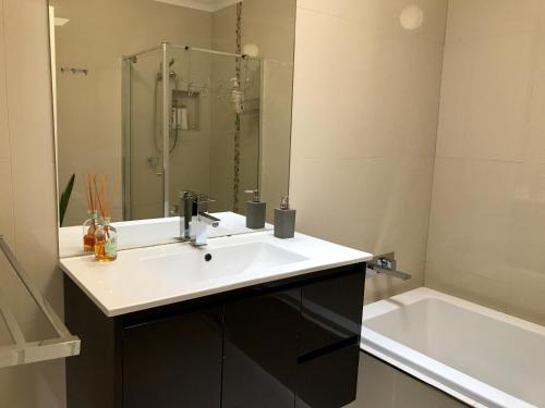 墨尔本Melbourne Inner City Holiday Home Near CBD & Flemington的浴室配有盥洗盆和浴缸。