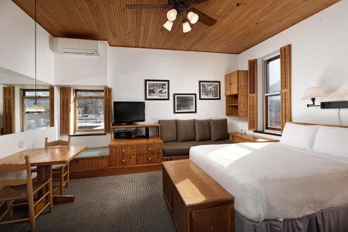 阿斯潘Independence Square 311, Best Location! Hotel Room with Rooftop Hot Tub in Aspen的一间卧室配有一张床、一张桌子和一张沙发
