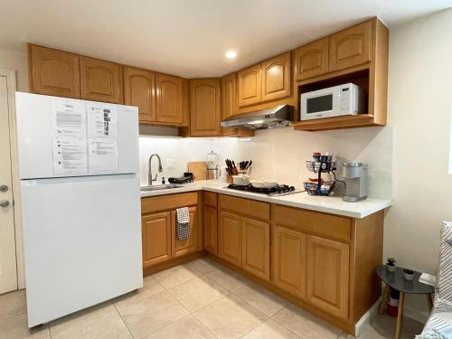 达利城9AM Check-in Coastal Getaway - Luxe Suite near Cliff, Lake & Local Shops的厨房配有木制橱柜和白色冰箱。