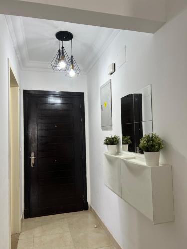 MadinatyGrand Madinaty 2BR Home-EID Mubarak的走廊上设有黑色的门和两盆植物