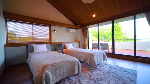 热海Alivio ATAMI的一间卧室设有两张床和大窗户