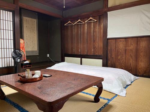 富士吉田市OSHI-KIKUYABO Mt-Fuji Historic Inn的一间卧室配有一张床和一张木桌