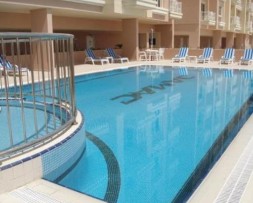 迪拜Huge Entire apartment for Couples ,families & Groups -up to 5 Guests- with free pool, steam & Sauna ,JVC,Dubai的酒店设有一个大型游泳池,游泳池内摆放着蓝色的椅子