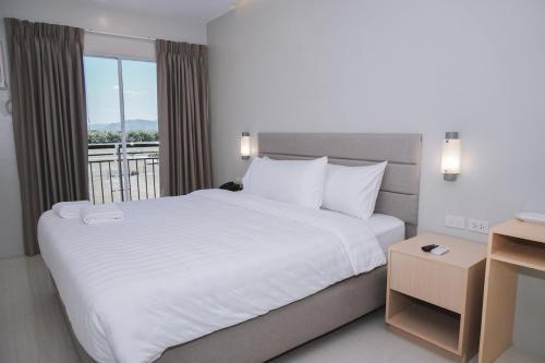 Ma. Awani Hotel & Suites的一间带一张白色大床的卧室和一个阳台