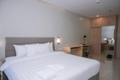 Ma. Awani Hotel & Suites的卧室配有一张白色大床和一张书桌