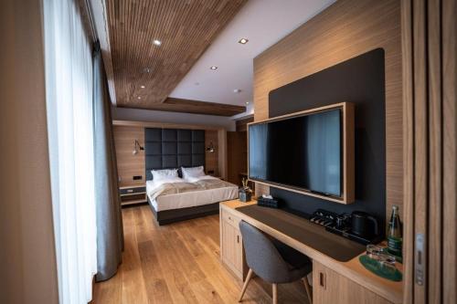 萨尔费尔德Kulmberghaus Resort的一间卧室配有一张床和一张书桌及电视