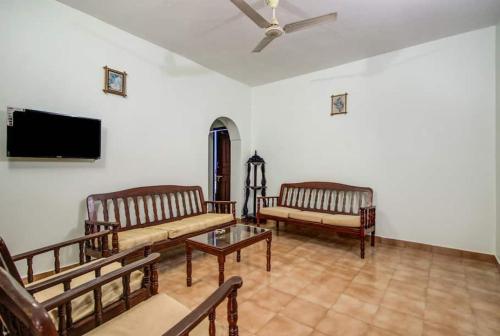 卡兰古特Super OYO Pravin Holiday Homes的客厅配有长凳和平面电视