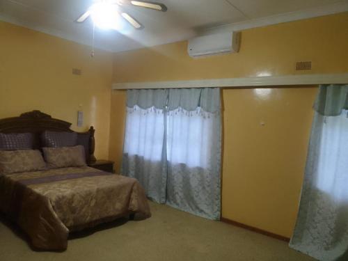 PrieskaHolope Self-Catering Accomm的一间卧室配有床和带窗帘的窗户