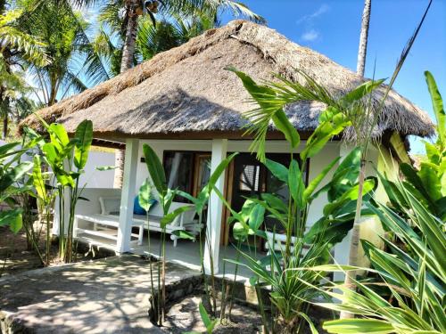 塞隆贝拉纳克Tiki Boutique Hotel Lombok的海滩上小屋,拥有茅草屋顶