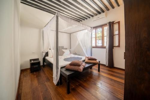 吉汶瓦Beachfront Villa Hideaway ZanzibarHouses的一间卧室设有一张天蓬床和木地板。