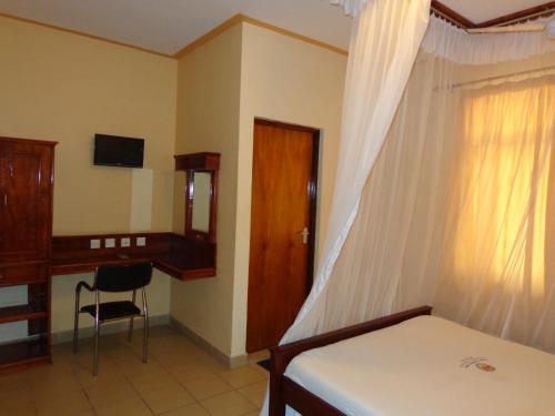 蒙巴萨福尔克斯旅馆的一间卧室配有一张床、一张桌子和一把椅子