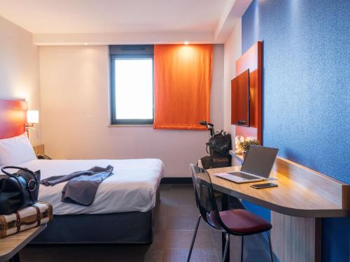 阿利仙罗马斯-瓦伦斯TGV车站宜必思尚品酒店的酒店客房配有一张床、一张书桌和一台笔记本电脑