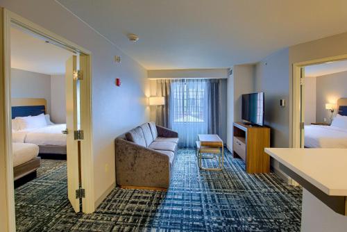 南本德Homewood Suites by Hilton South Bend Notre Dame Area的酒店客房设有沙发、床和电视。