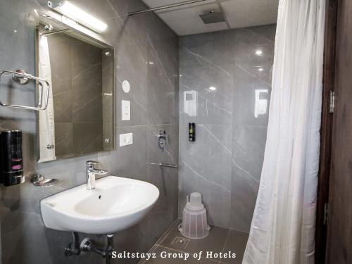 古尔冈Saltstayz Hotel Huda City Centre的一间带水槽、镜子和淋浴的浴室
