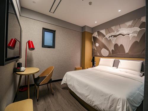 包头尚客优精选包头昆都仑区科技大学酒店的酒店客房设有一张大床和一张桌子。