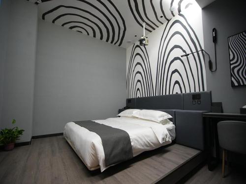包头尚客优悦包头昆都仑区白云路恒大酒店的一间卧室配有一张床,墙上配有旋转图案