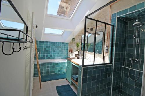 La cle des champs的浴室铺有蓝色瓷砖,设有淋浴和盥洗盆。