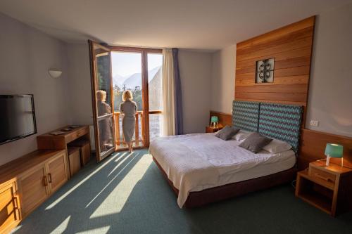 博维茨Hotel Boka的一间卧室配有一张床和电视,另一人眺望窗外