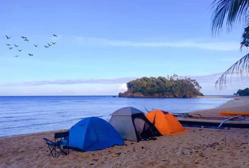 RomblonKOKONUT HUT RETREAT & CAMPING SITE RENTAL的两顶帐篷,位于海滩上,靠近水域