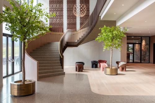 迪温特Van der Valk Hotel Deventer的大堂设有楼梯和两棵树及椅子