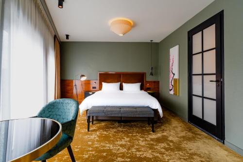 阿姆斯特丹Hotel Mai Amsterdam的一间卧室配有一张床和一张玻璃桌子及椅子