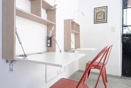 布宜诺斯艾利斯PH Palermo Hostel的厨房配有白色的柜台和红色的椅子