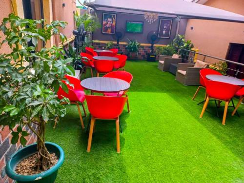 伊凯贾ERiTH APARTMENT & SUITES的庭院里设有红色的桌椅和植物