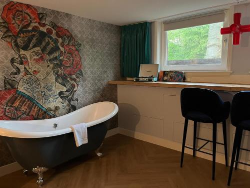 乌得勒支MUZE Hotel Utrecht的带浴缸的浴室,墙上有绘画作品