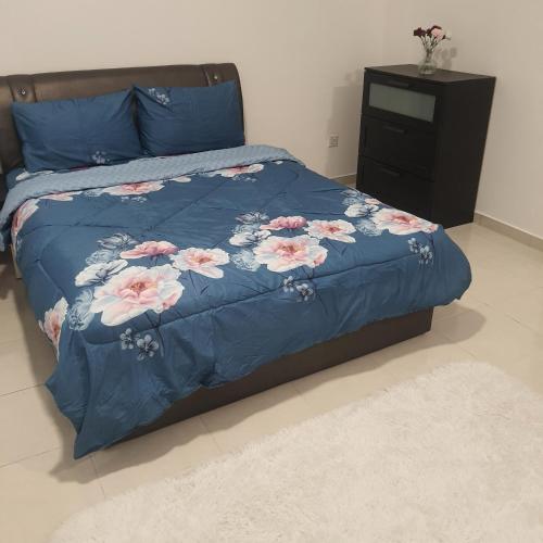 Bandar Puncak AlamD Laman Haris Homestay的一张带蓝色棉被的床,上面有粉红色的花朵
