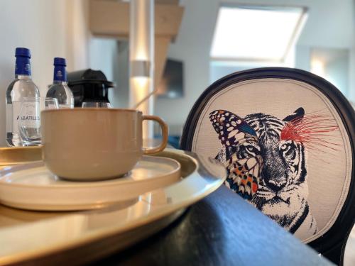 保拉扎克Richard Lequet Domaine gastronomique du Val d Atur的一张画有老虎图画的盘子,一张桌子上拿着杯