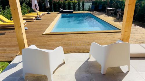 新皮尼亚尔Chalé do Vale的甲板旁的游泳池,配有两把白色椅子