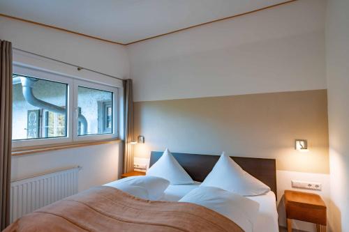 容霍尔茨Am Hof Jungholz的卧室配有带白色枕头的床和窗户。