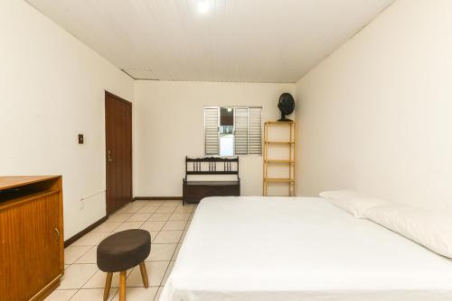 弗洛里亚诺波利斯Rental Florianópolis - Acomodações Residenciais的卧室配有白色的床和椅子