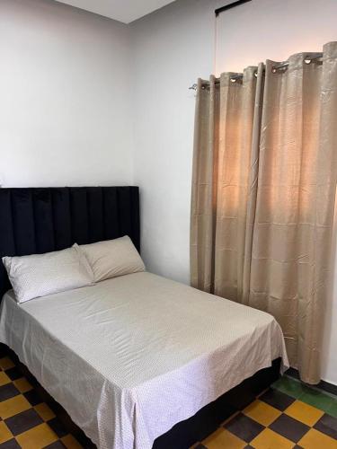 圣多明各APARTAMENTO ZONA COLONIAL R的一间卧室配有一张带黑色床头板和窗帘的床