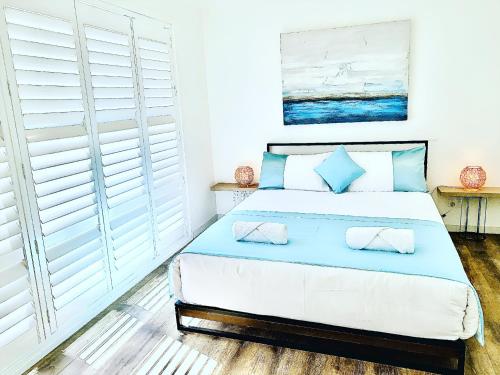 巴特曼斯贝Surfside Holiday Home 100m Beach的一间卧室配有一张带蓝色枕头的大床