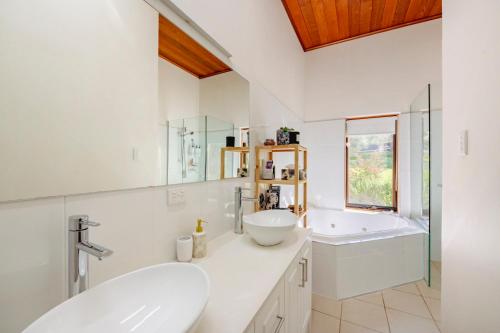 Blewitts SpringsAmongst the Vines Deluxe Retreat的白色的浴室设有2个盥洗盆和1个浴缸。