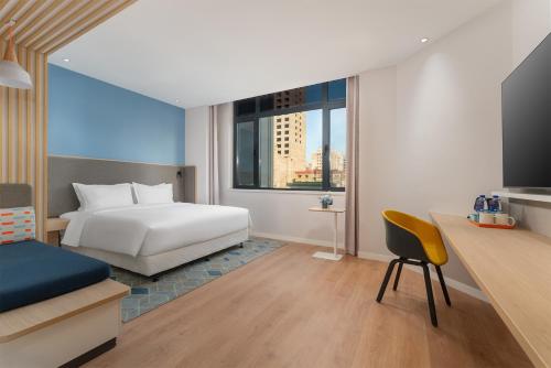 丹东丹东中心智选假日酒店的一间卧室配有一张床和一张书桌及电视