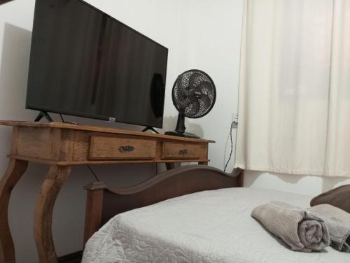 圣若昂-达巴拉Mini Casa Furnas - Capitólio MG的桌子上的电视,配有一张床和风扇