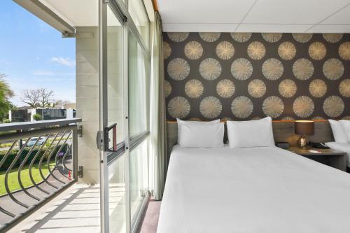 汉密尔顿Heartland Ambassador Hotel Hamilton的一间卧室设有一张床和一个阳台