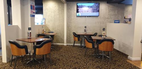 沃勒格尔Club Hotel Warragul的酒吧配有桌椅,墙上配有电视