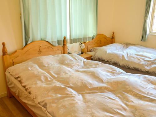 轻井泽Tree Village Karuizawa的卧室设有两张未铺床,设有窗户