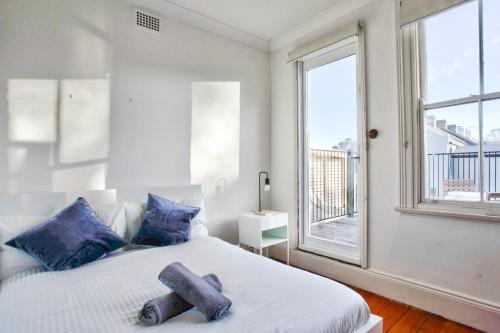 悉尼3 Bedrooms - Darling Harbour - Darghan Street 2 E-Bikes Included的一间卧室配有一张带蓝色枕头的床和一扇窗户。