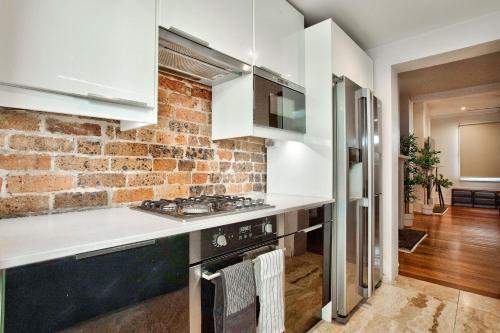 悉尼3 Bedrooms - Darling Harbour - Ada Place的厨房配有白色的柜台和砖墙