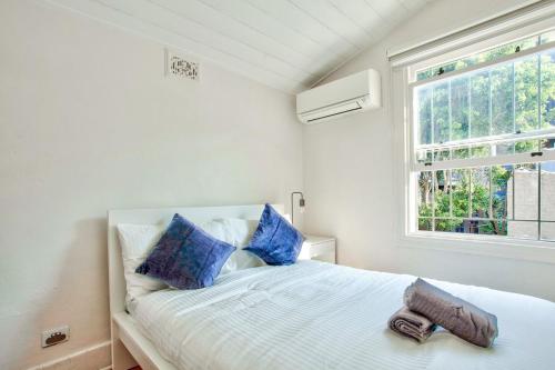悉尼3 Bedrooms - Darling Harbour - Ada Place的一间卧室配有一张带蓝色枕头的床和一扇窗户。