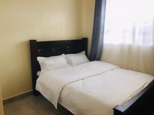 内罗毕Citux Homes的一间卧室配有一张带白色床单的床和一扇窗户。