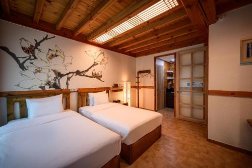 全州市Jeonju Wangyijimil Hanok Hotel的一间卧室设有两张床,墙上挂着一幅画