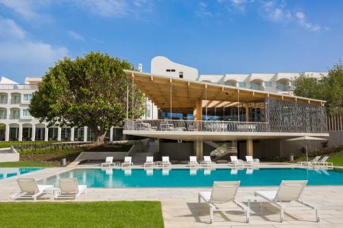 塔维拉OZADI塔维拉酒店 的一个带椅子的游泳池和一座建筑的度假胜地