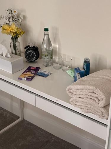 伦敦Home from Home Cosy B&B的白色的书桌,带时钟、一瓶酒和眼镜